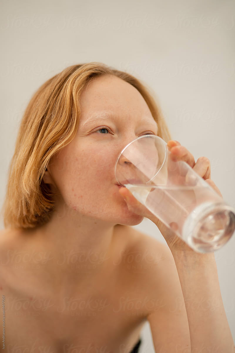 Portrait of young albino woman with glass of water