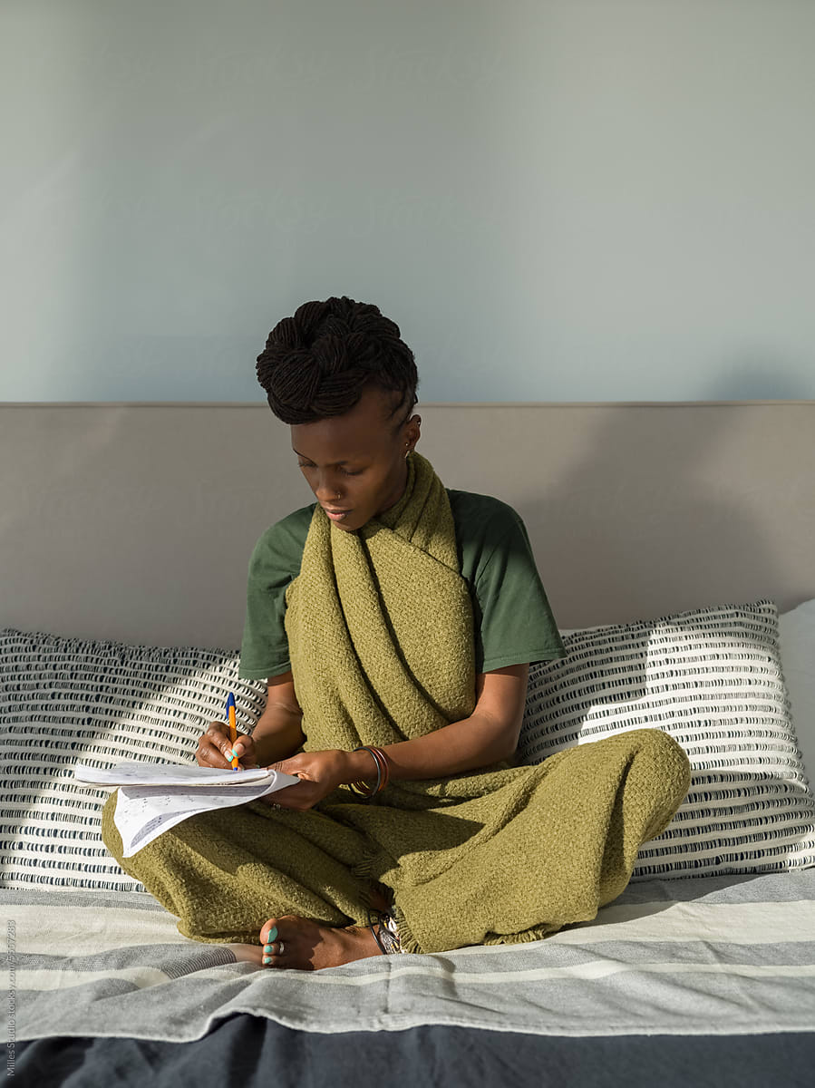 Black woman studying on bed at home