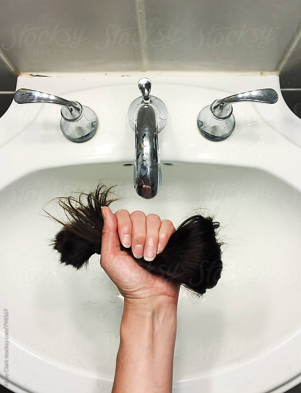 Fist holding hunk of cut hair over sink