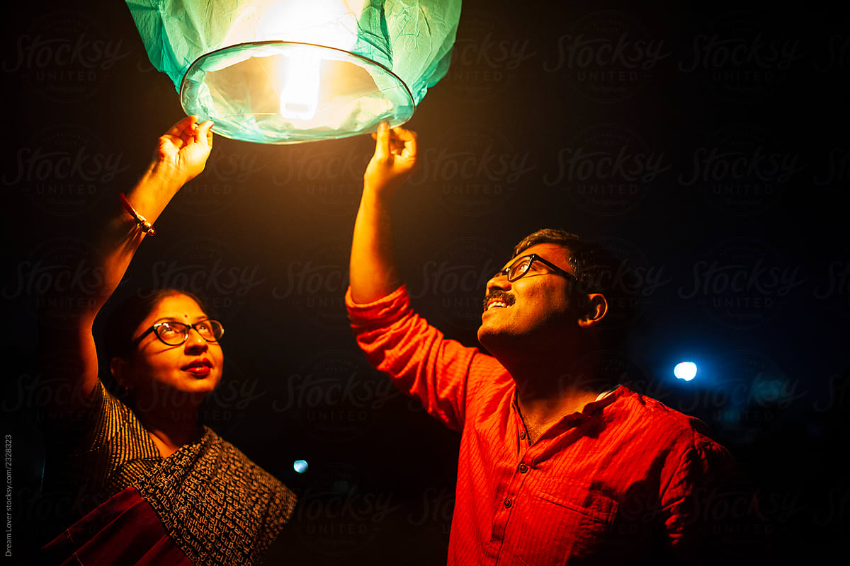 Middle Aged Couple Holding Sky Lantern To The Sky At Twilight