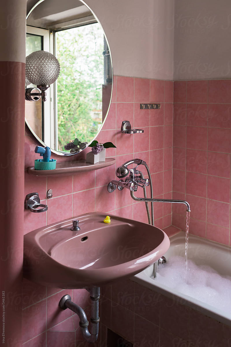 Filling the Bathtub in a Retro Pink-Tiled Bathroom