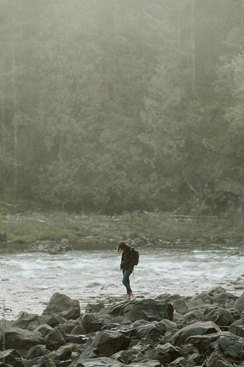 Young woman walking near a misty river in a forest in Washington State