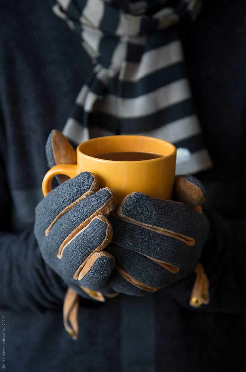 yellow cup in male hands in grey gloves