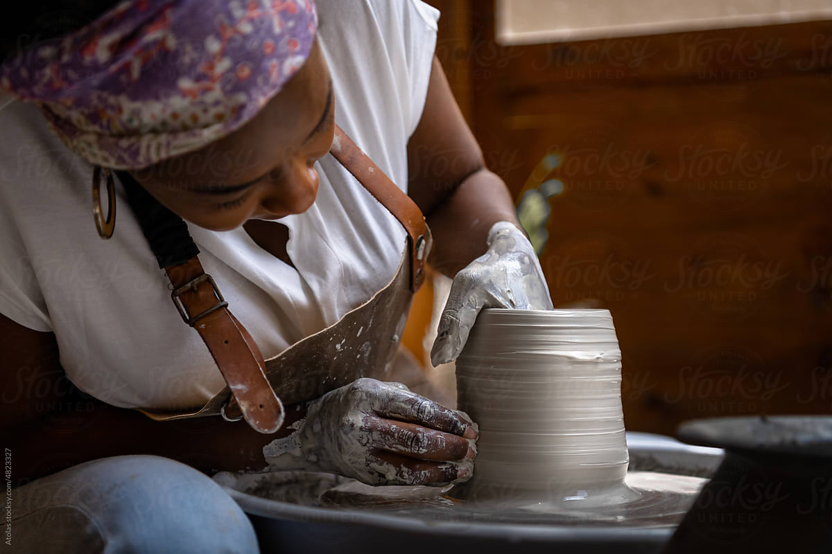 Woman shaping clay edges on pottery wheel