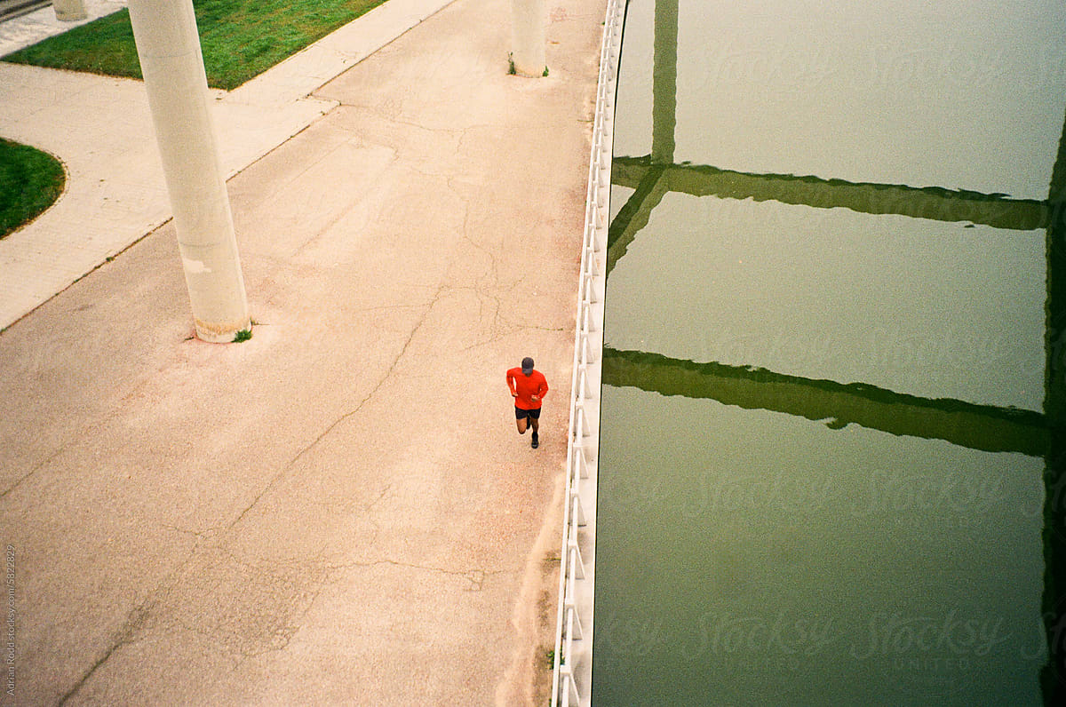 A black athlete running along the lakeshore of an empty park