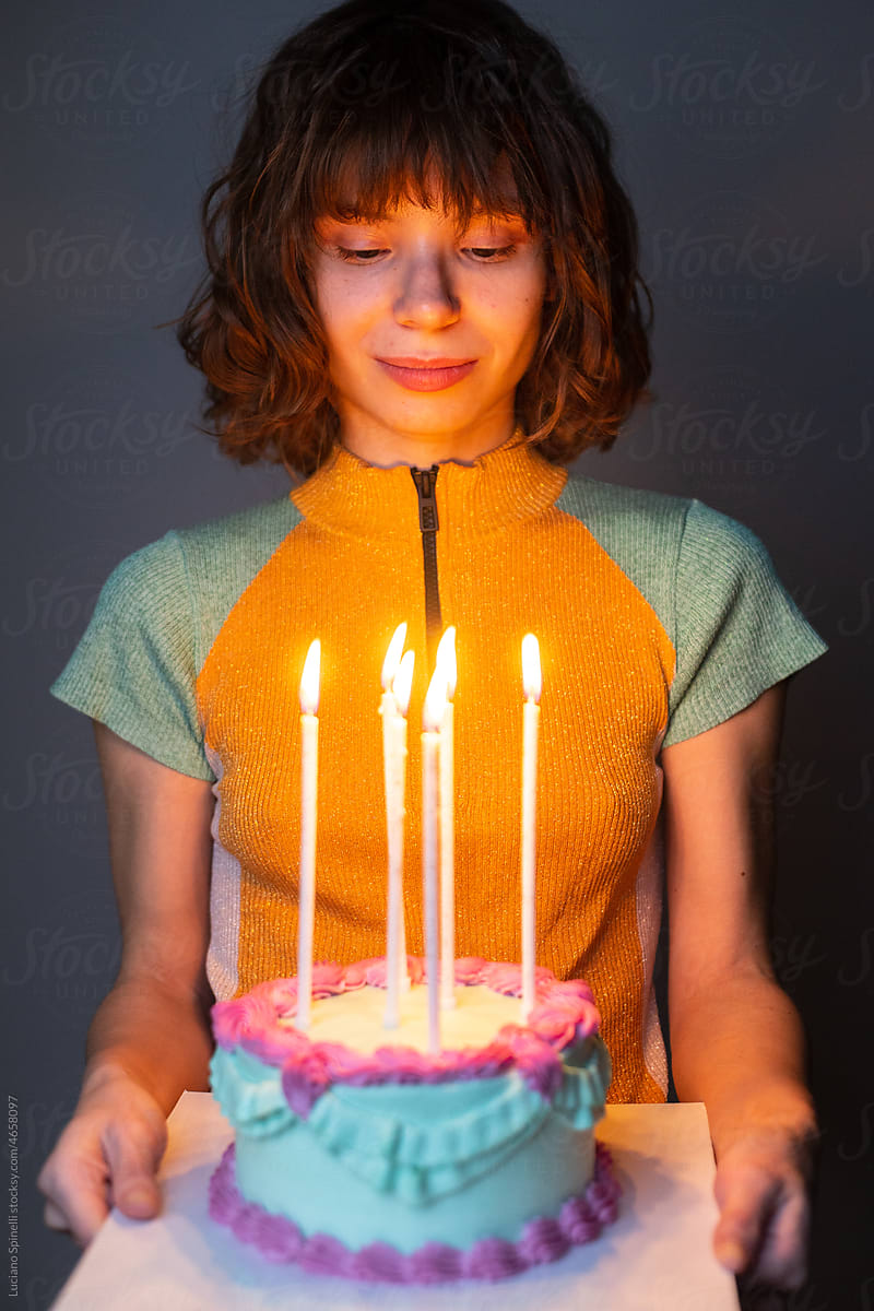 Birthday girl smiling with a blue cake with long candles in her hands