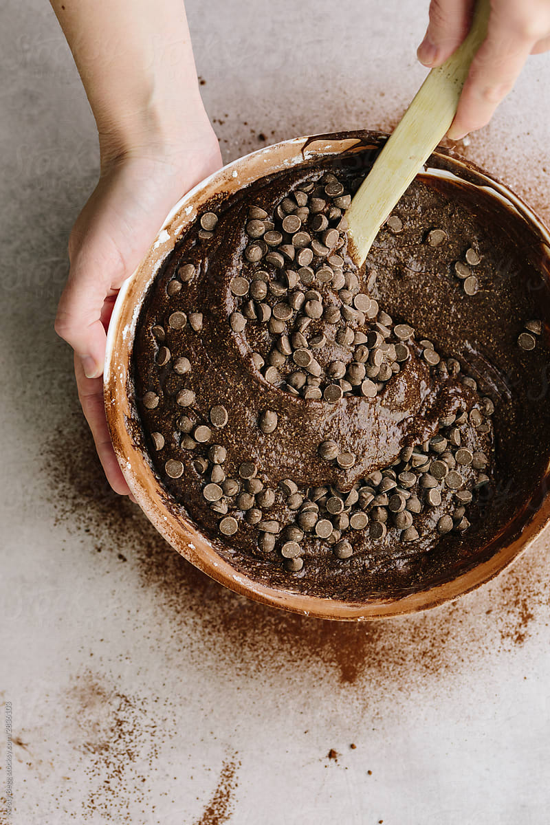 Woman Stirring Chocolate Chip Drops Into Brownie Cake Batter By Stocksy Contributor Kirsty
