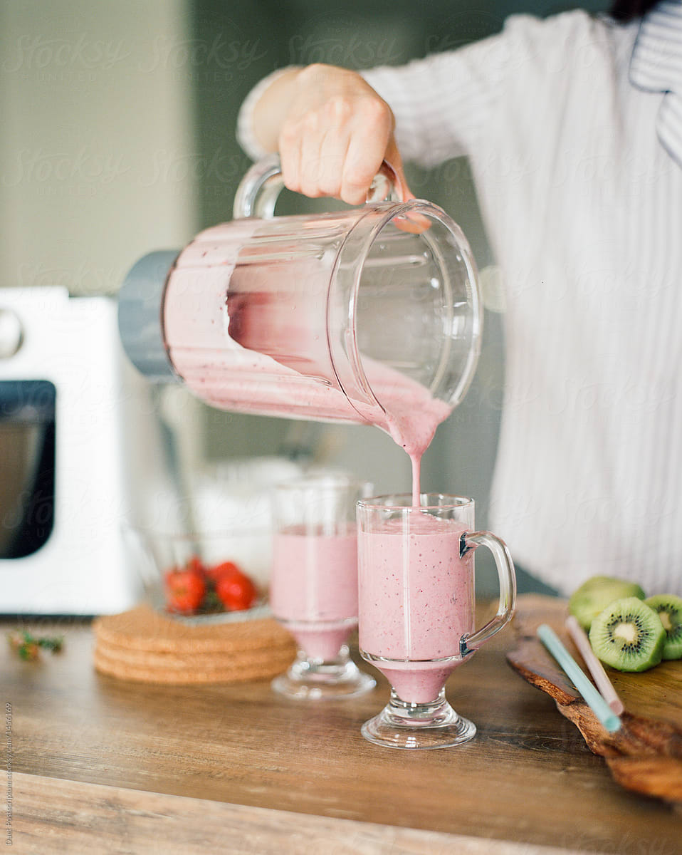Woman pouring smoothie to glasses