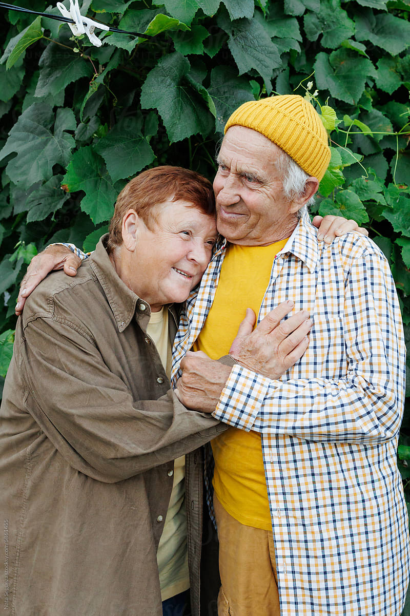 Elderly Couple Embracing in Garden During Summer