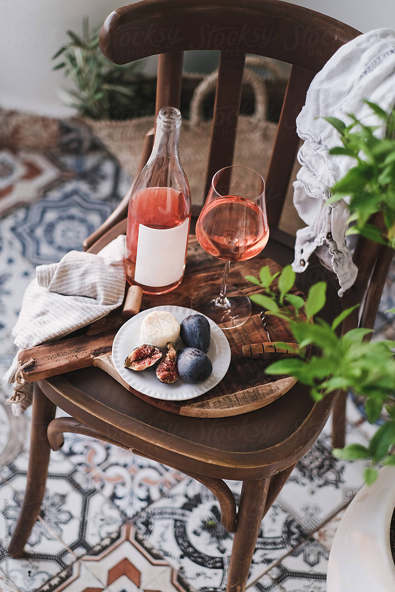 Bottle and glass of rose wine with snacks over chair