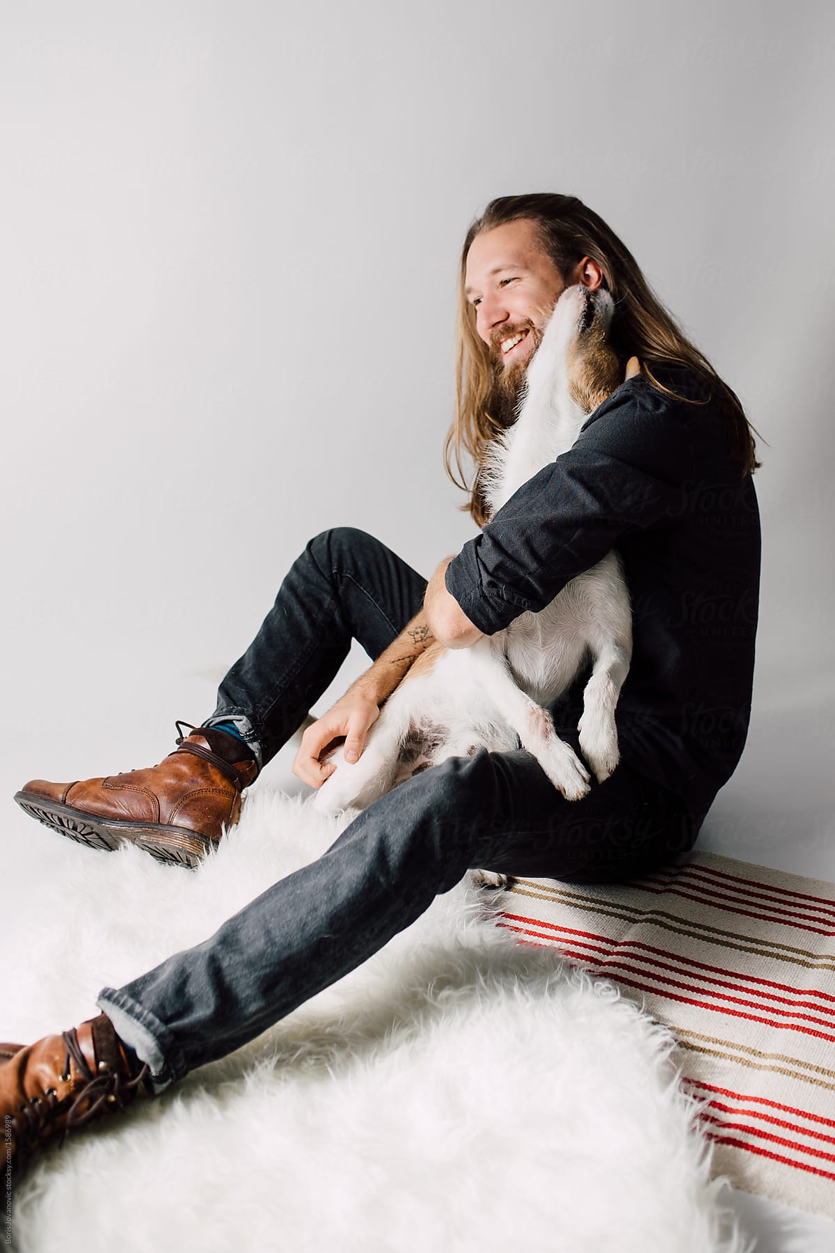Elegant man cuddles his dog in studio