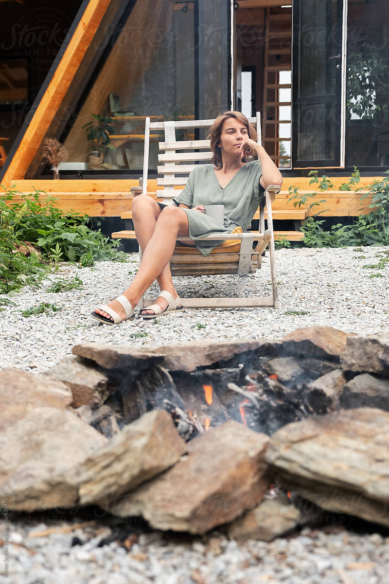 Thoughtful woman resting near fire pit