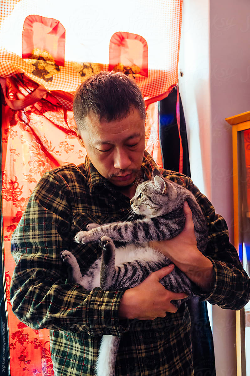 An asian man staying at home with his pet cat
