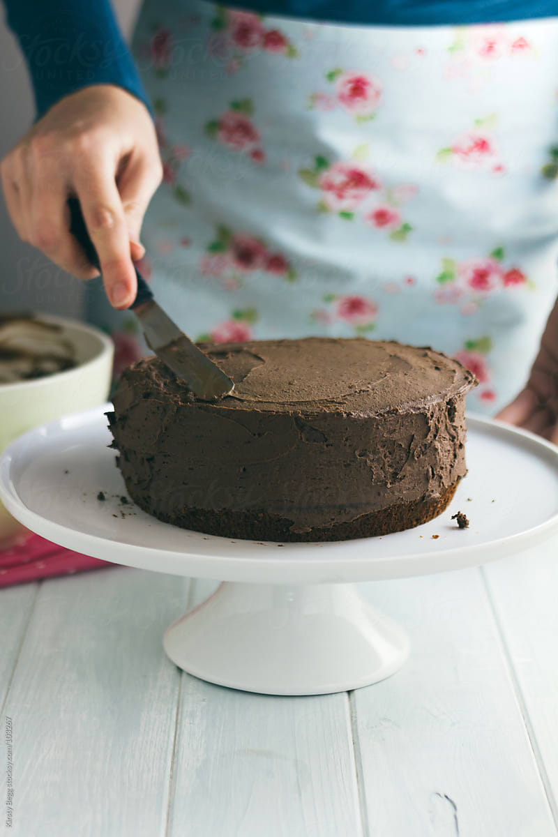 Woman frosting a chocolate cake