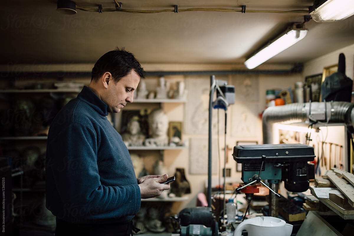 Man Using His Mobile Phone In A Workshop