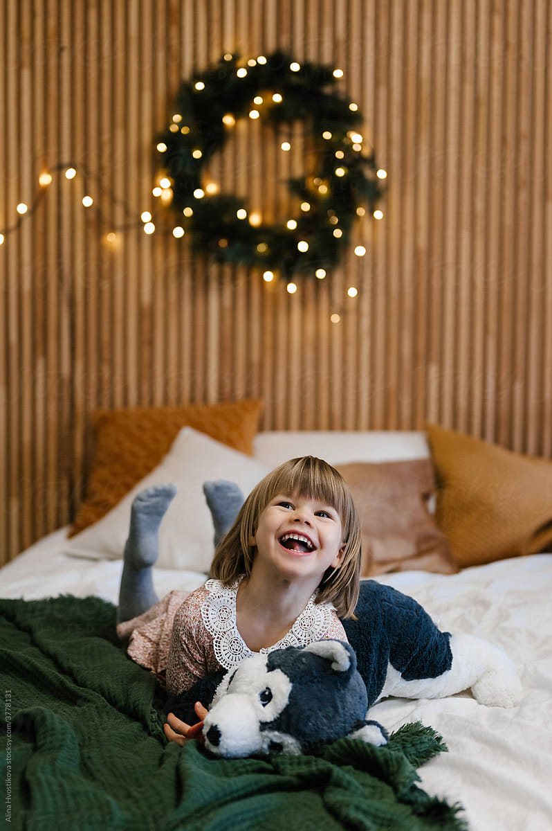 Laughing girl with toy on bed