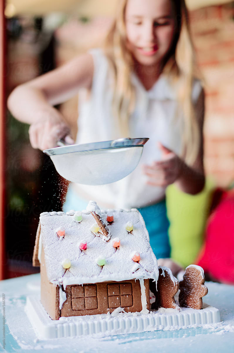 Icing snows down onto a gingerbread house at christmas