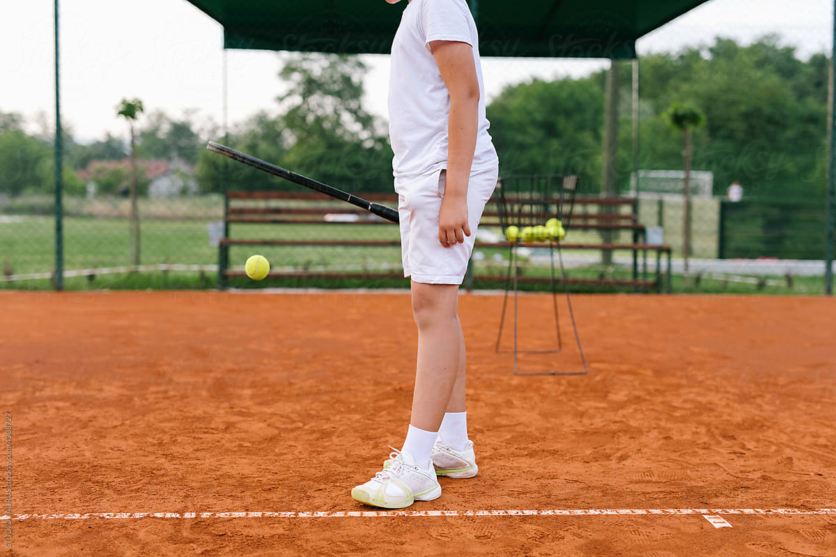 Unknown boy on a tennis court practice tennis