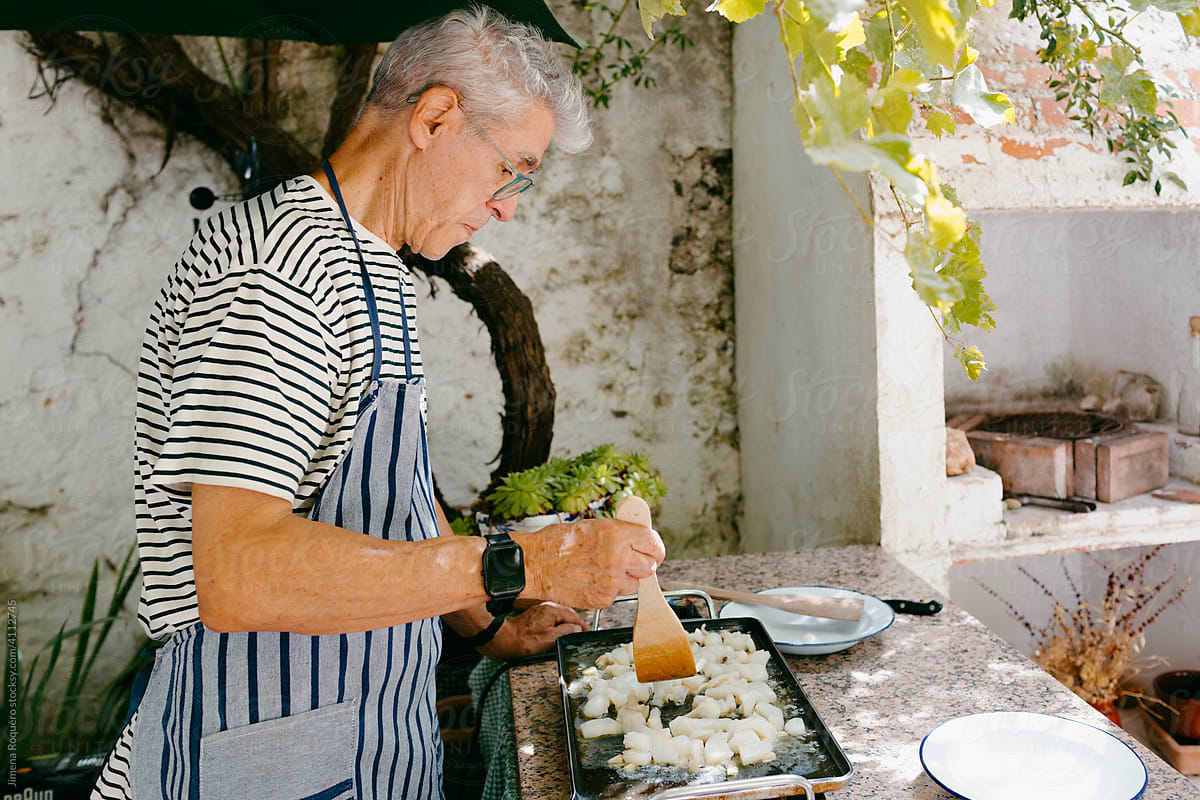 Elderly man preparing seafood dish in outdoor griddle