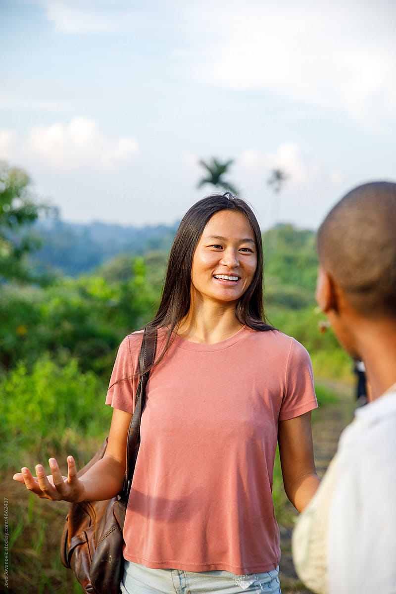 Asian woman chatting with friend while out in nature