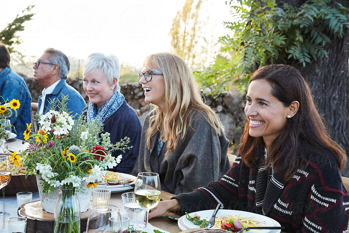 Friends laughing together at outdoor dinner in backyard