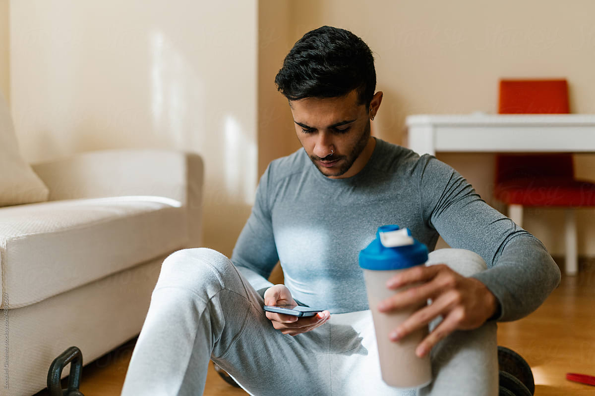 Sportsman with protein shake using smartphone