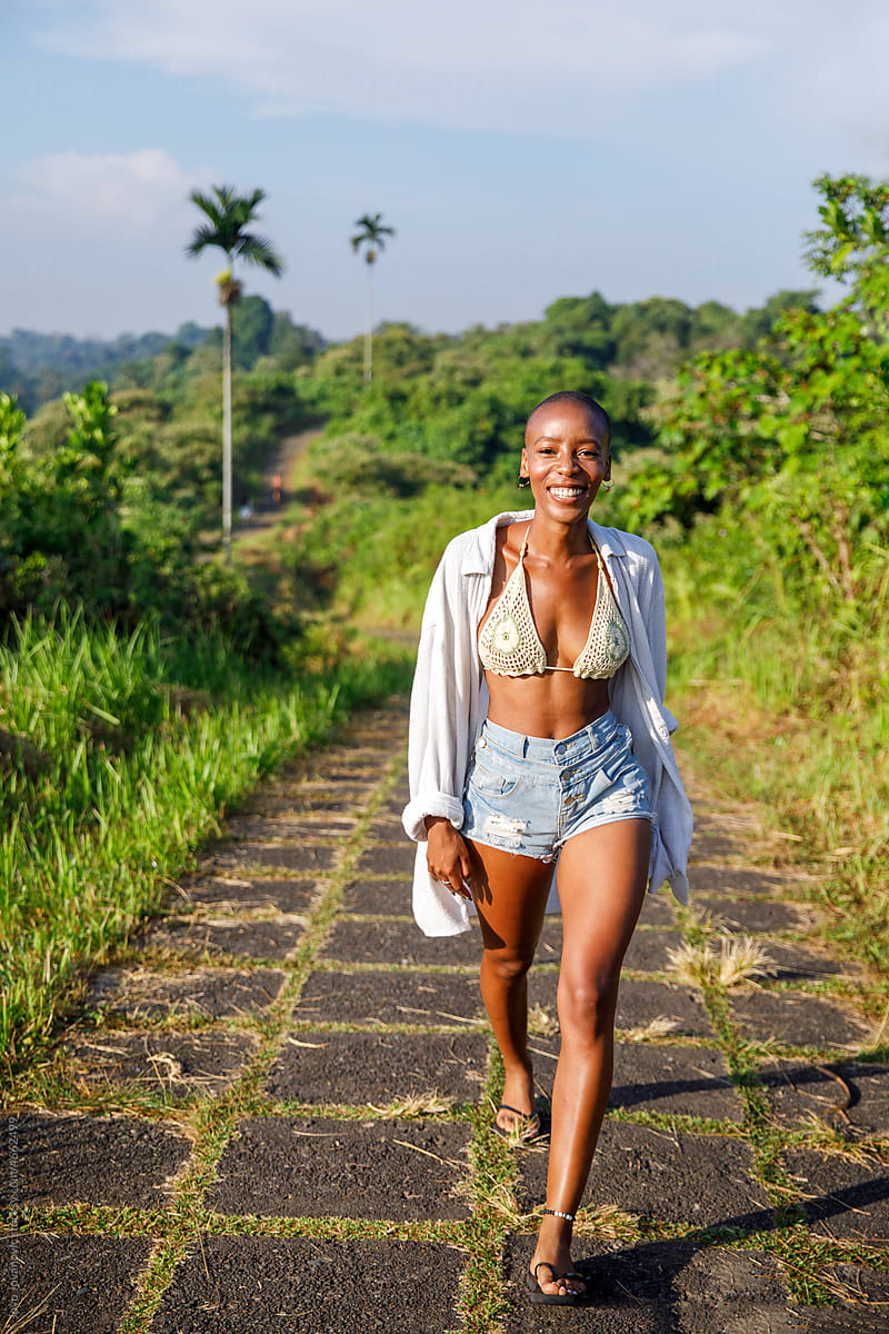 Trendy young black woman walking in nature in bikini