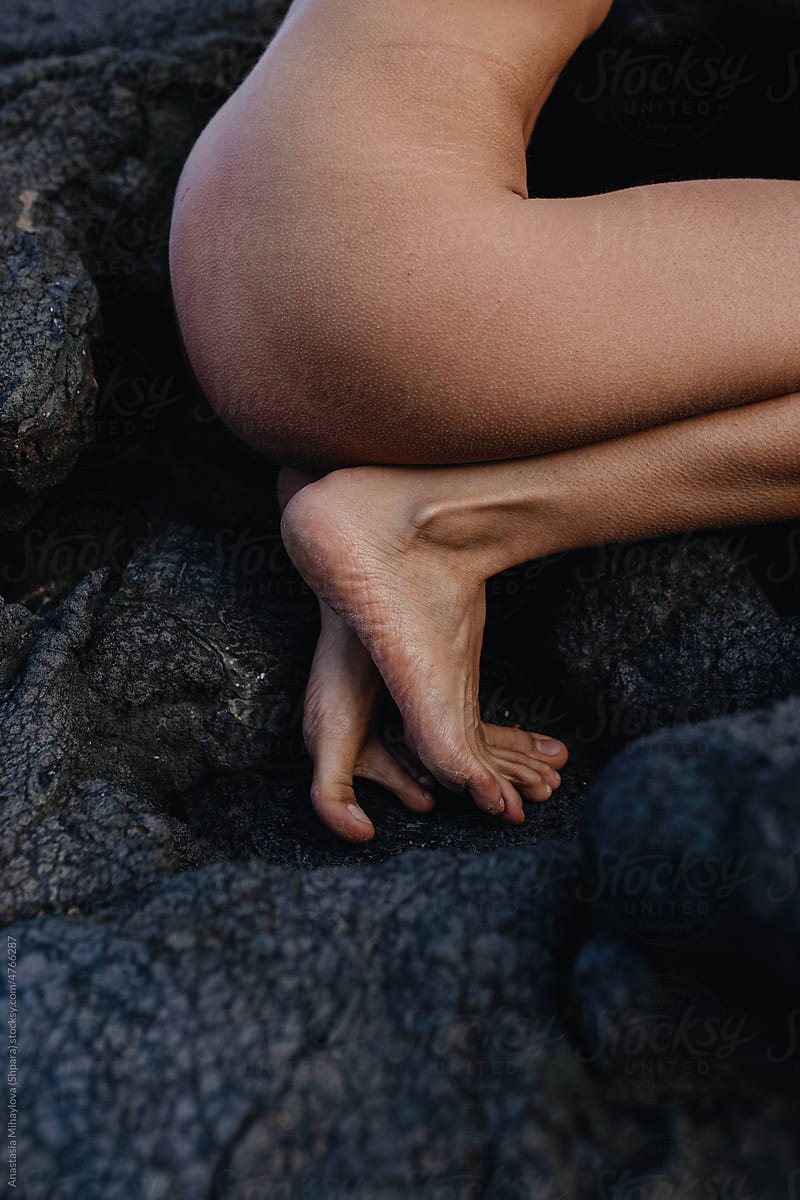 Naked woman squatting on black solid lava in Iceland