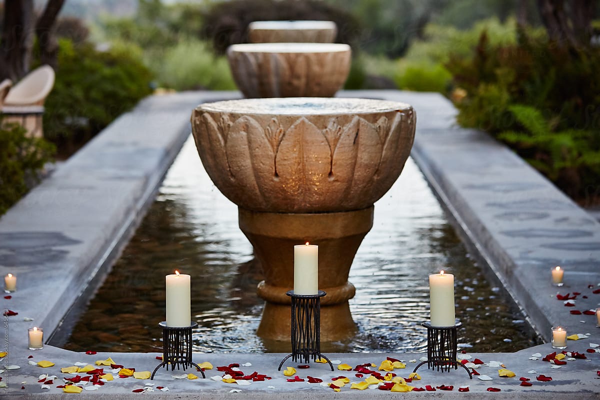 Outdoor spa at dusk with candles and rose petals