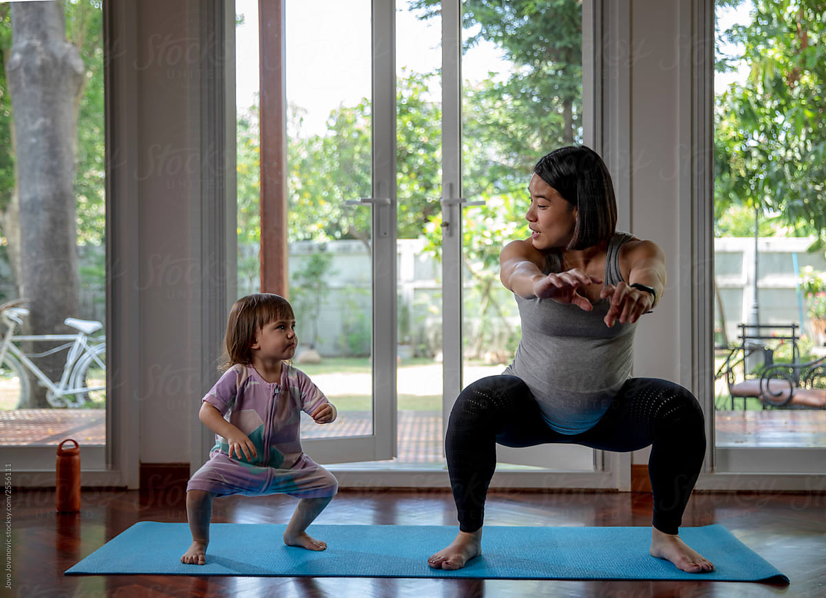 Little girl copying mom during exercise at home