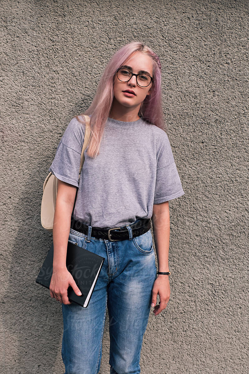 Beautiful girl with pink hair in casual outfit with beige rucksack and black notebook