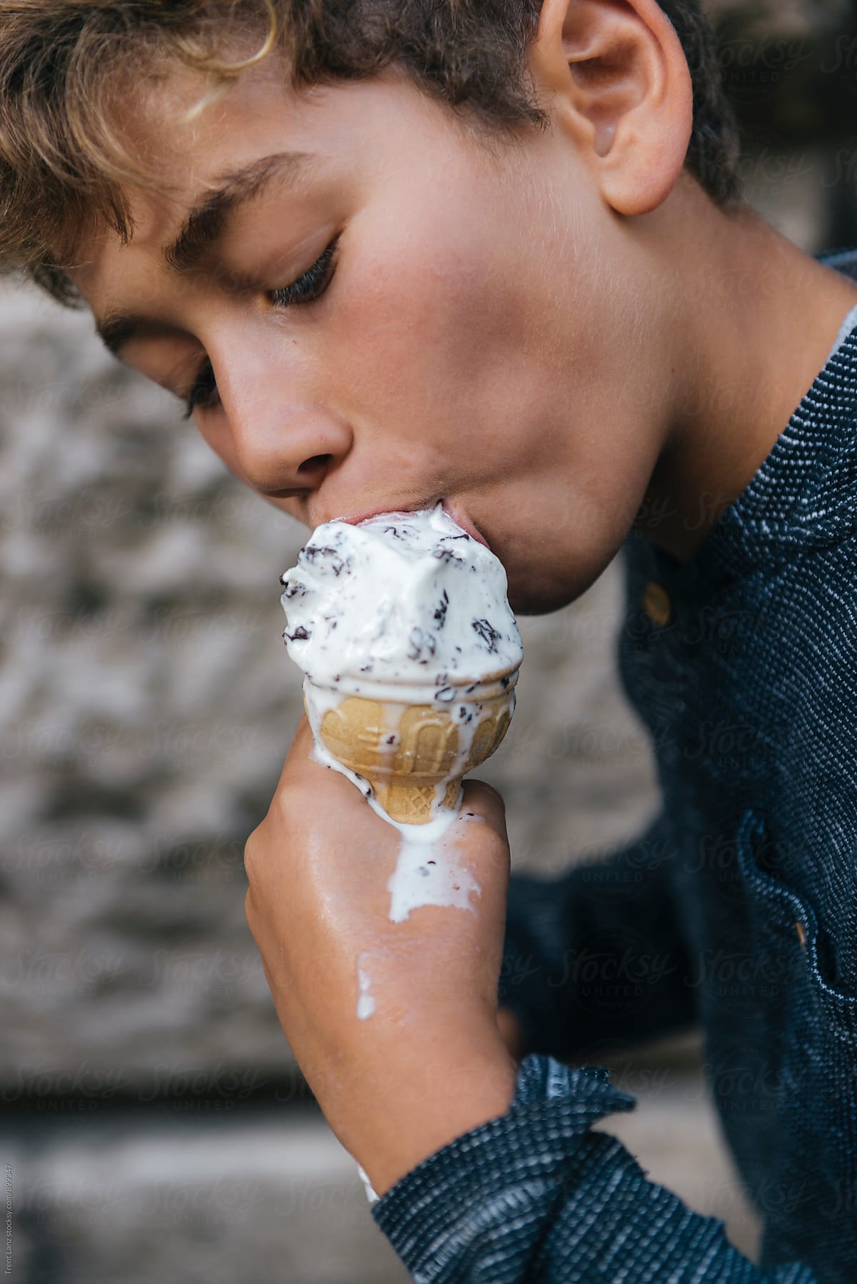 Boy eating melted ice cream while looking down