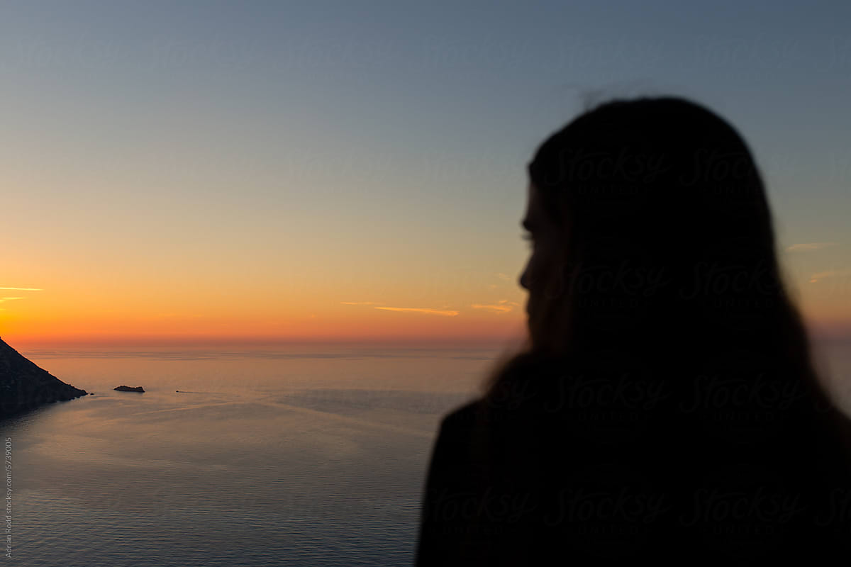 Close-up of the silhouette of a woman looking at the sunset on the sea