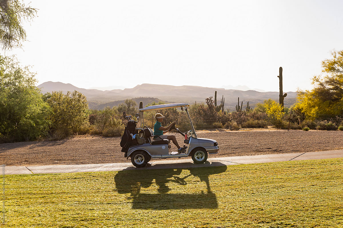 Pretty Senior Citizen driving golf cart on golf course