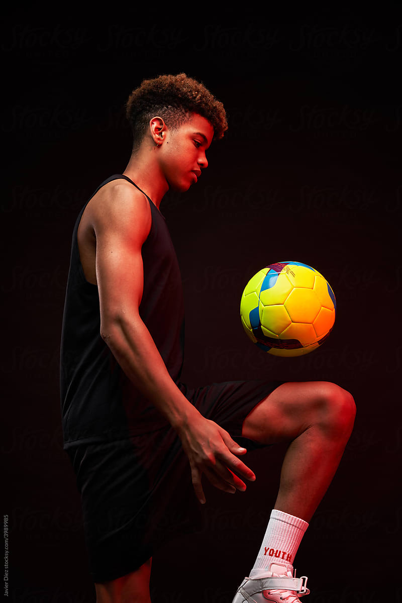 Black sportsman kicking soccer ball