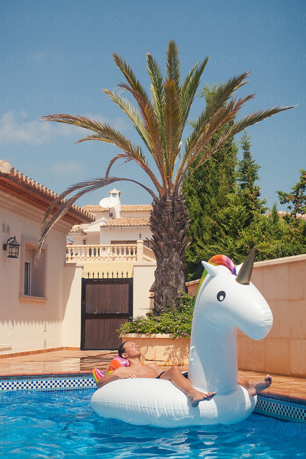 Teen boy lying on a big inflatable unicorn in a swimming pool