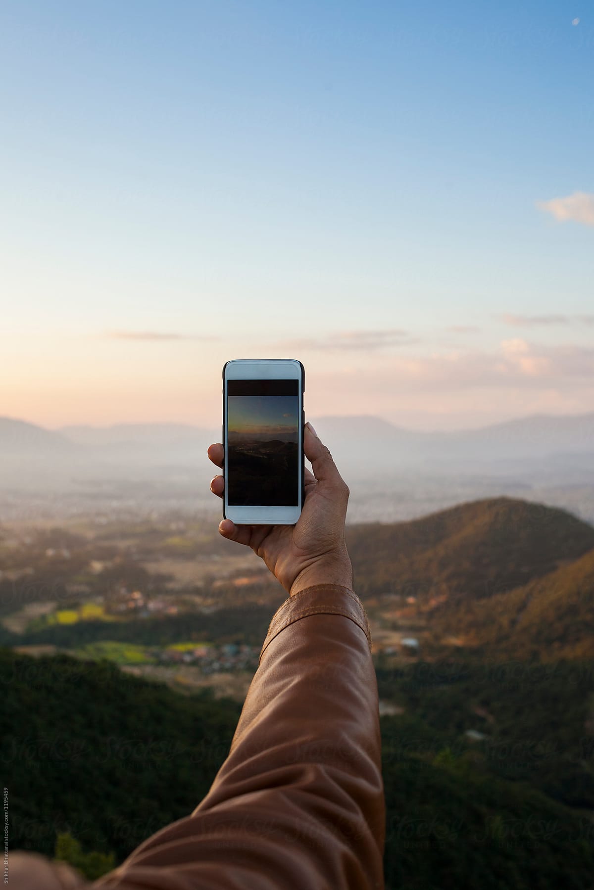 Hand with a smartphone against the himalayan landscape.