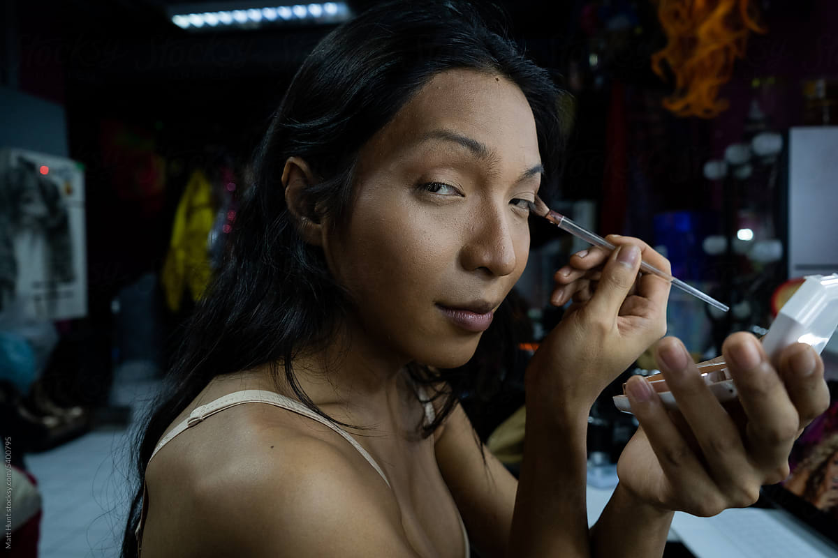A hai transgender aritst finishes her eye makeup before a show