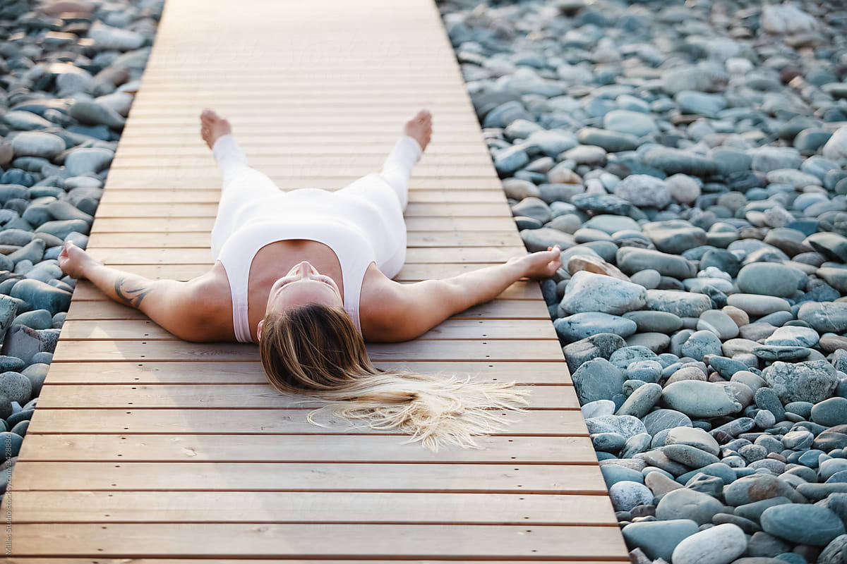 Woman meditating in Savasana pose on beach