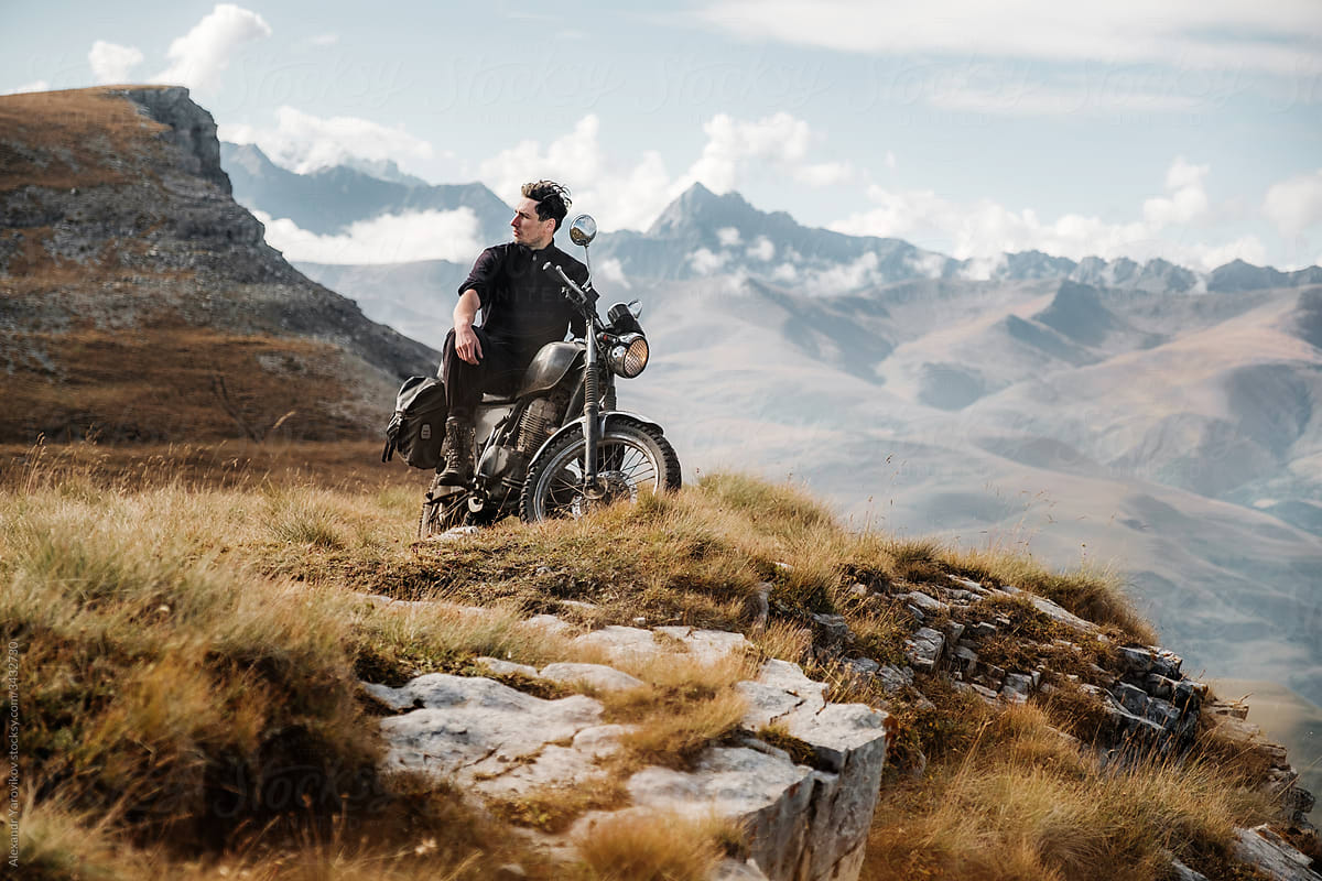A rider sits on a motorcycle at the top of a mountain