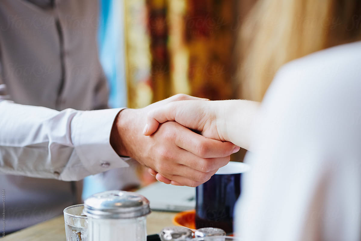 Business agreement being made with a handshake in a cafe