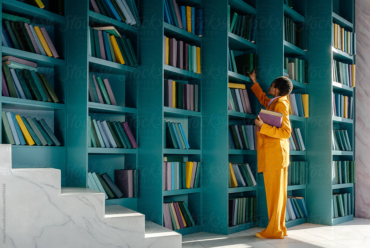 Female in yellow suit picking books from shelves