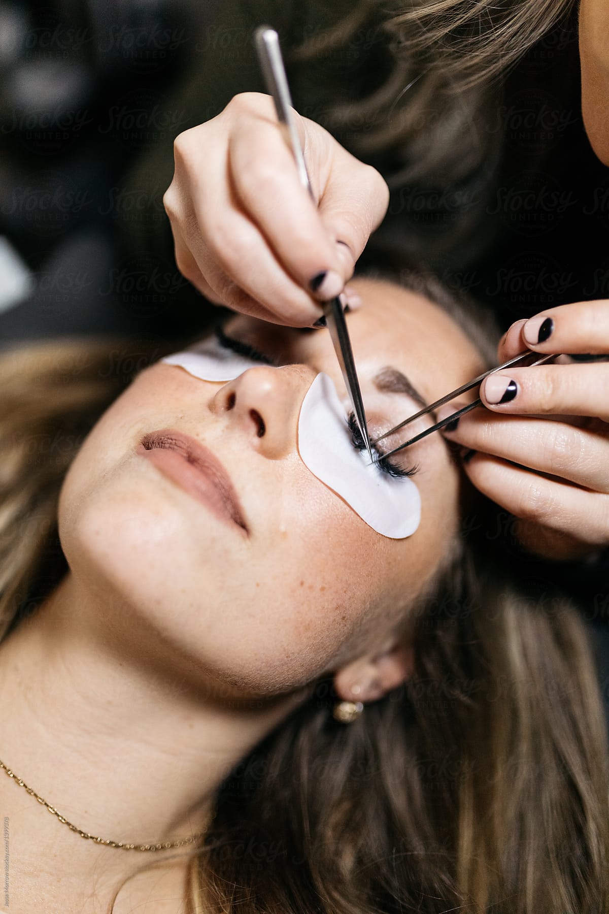 Young woman getting lash extension cosmetology laying down in small business studio