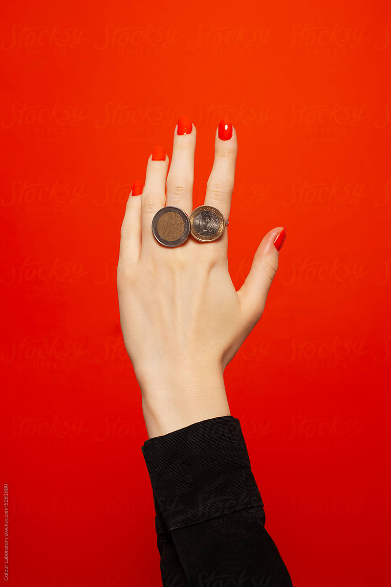 Hand with red nails with rings made of coins