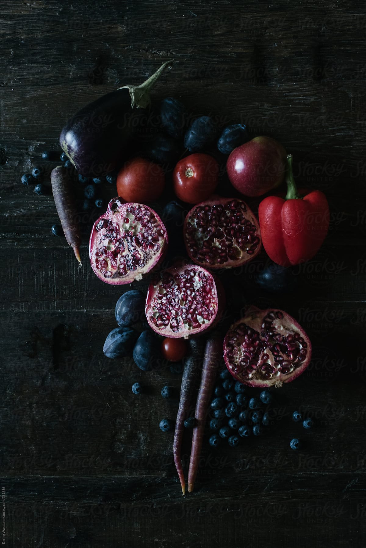 Dark purple and red fruits and vegetables styled on dark wood table