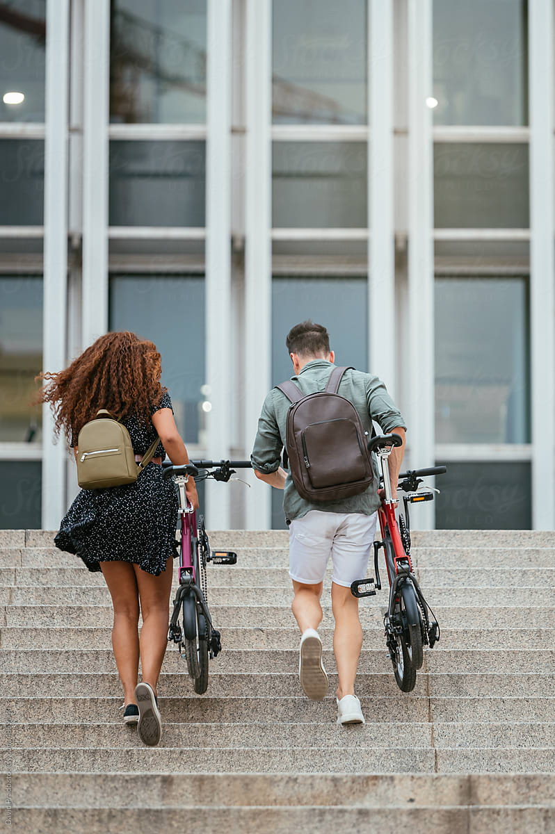 Diverse cyclists walking on steps