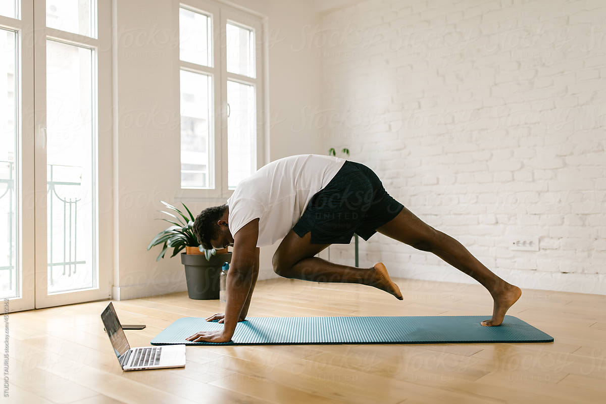 Man following online yoga class on the computer