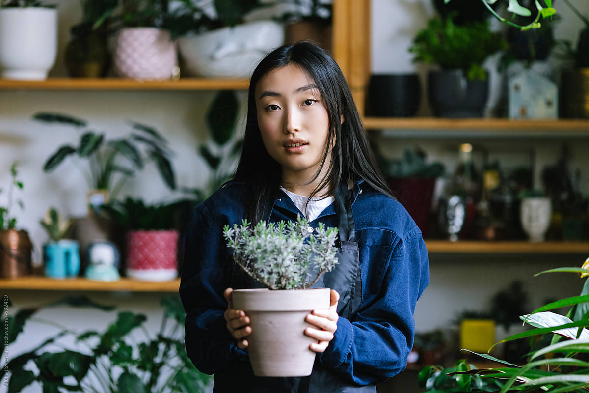 Flower employee with houseplant in working space at store