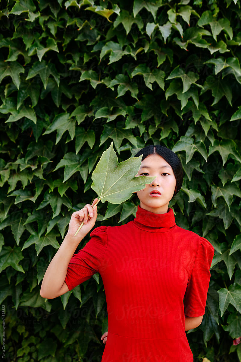 Dreamy woman holding green leaf in park