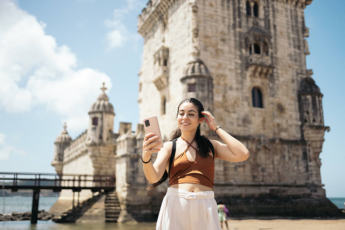 Young tourist woman taking selfies with her smartphone at Belem tower
